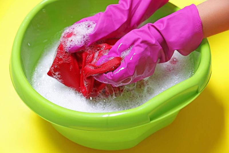 Woman soaking garment in soapy water.. 