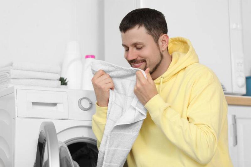 Man smelling laundry out of dryer. 
