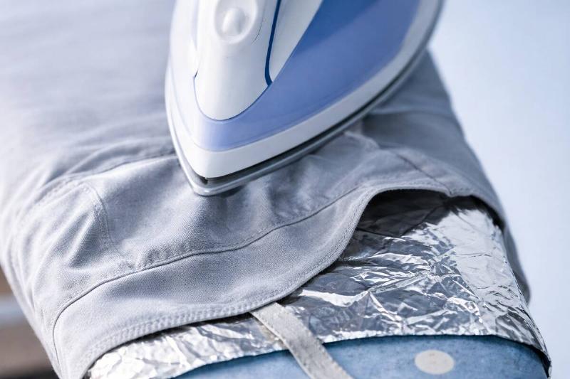 AI rendering of a piece of clothing being ironed, with a sheet of aluminum foil between the clothing and the ironing board