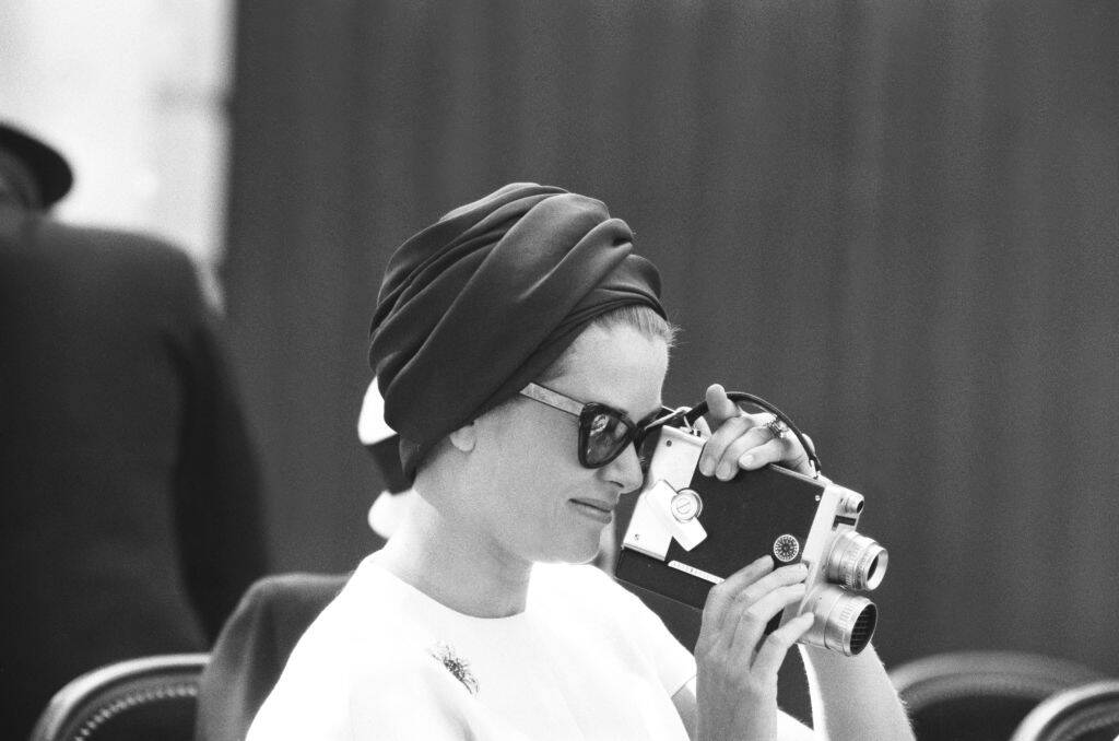 Grace Kelly holding a movie camera up to her face