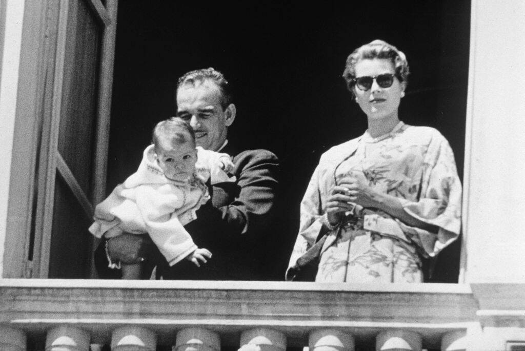 Prince Rainier holding Princess Caroline. Grace Kelly stands beside them