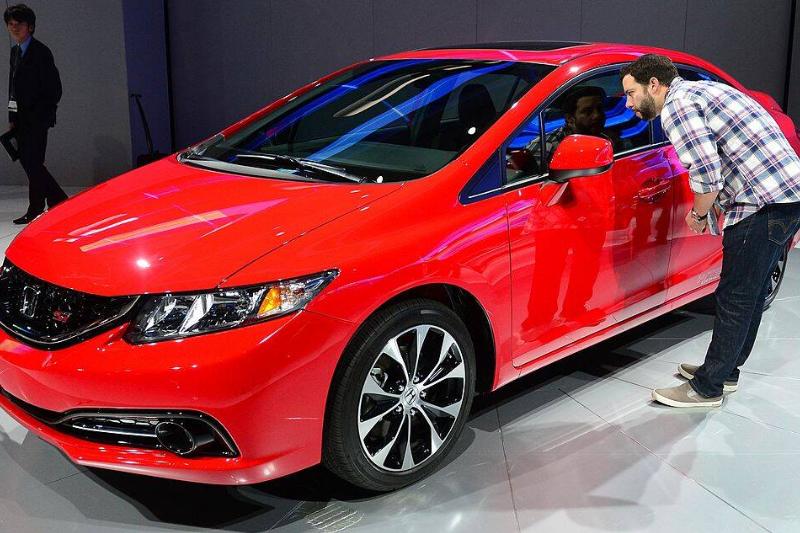 Man looking through the window of a red 2013 Honda Civic