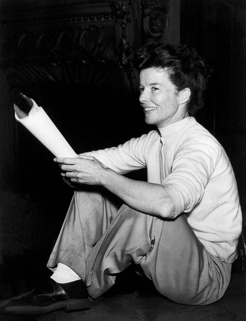 Katharine Hepburn sitting cross-legged, holding a script