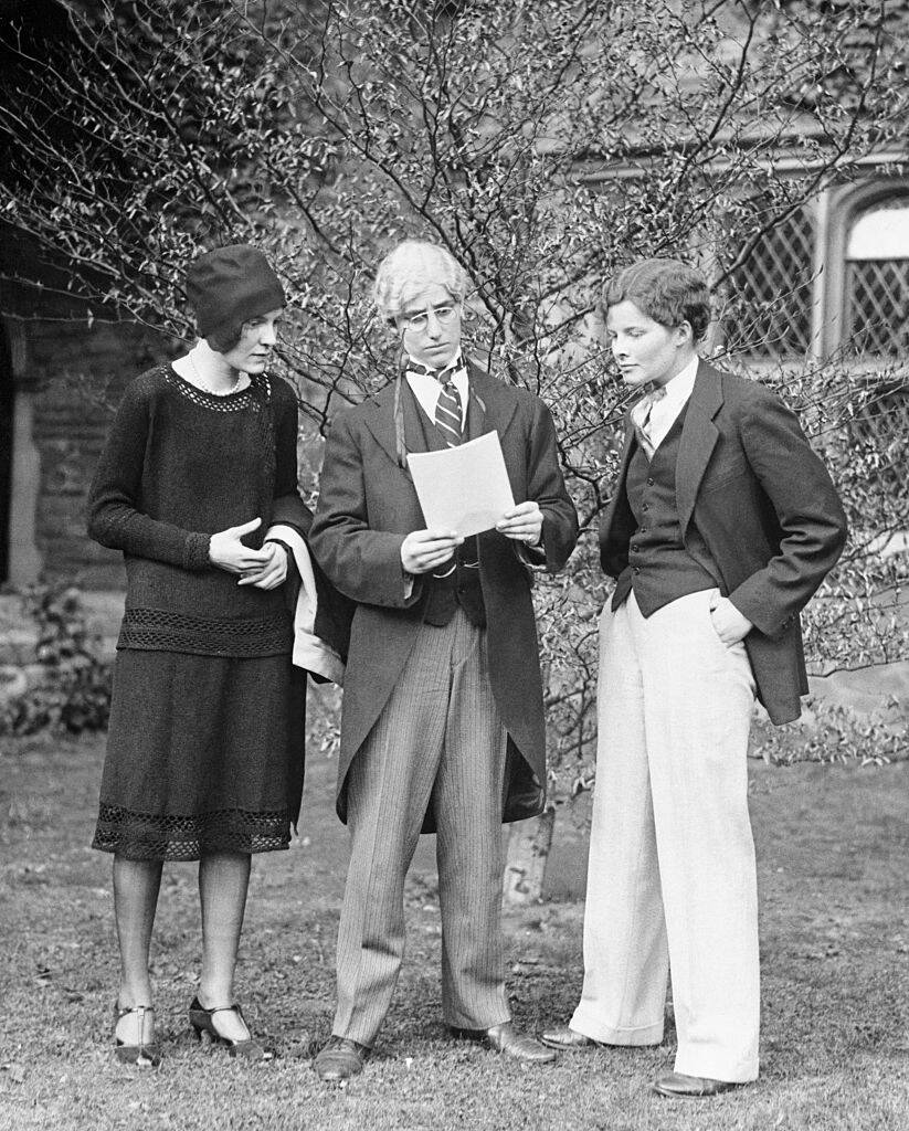 Margaret Barker, Elizabeth Stewart and Katharine Hepburn standing outside in costume, looking at a script