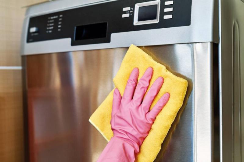 Hand cleaning the outside of a dishwasher. 