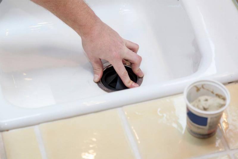 Hand moving garbage disposal in sink. 