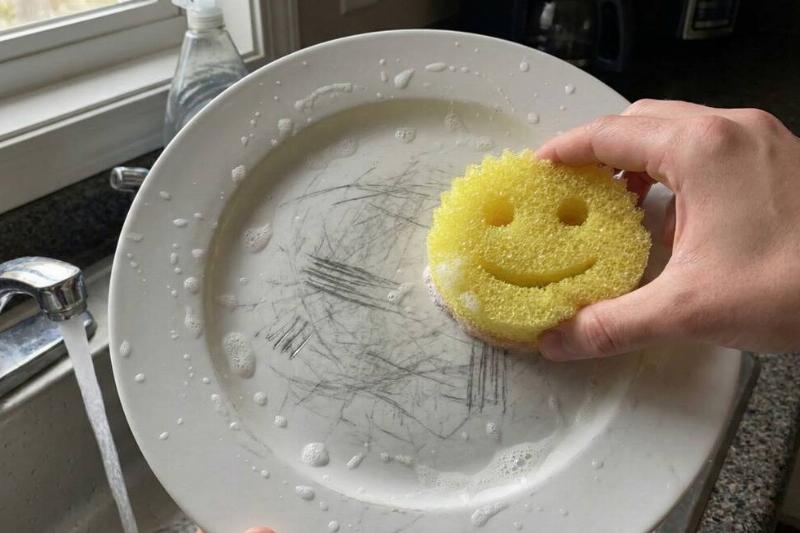 A Scrub Daddy being used to wash a scratched plate. 