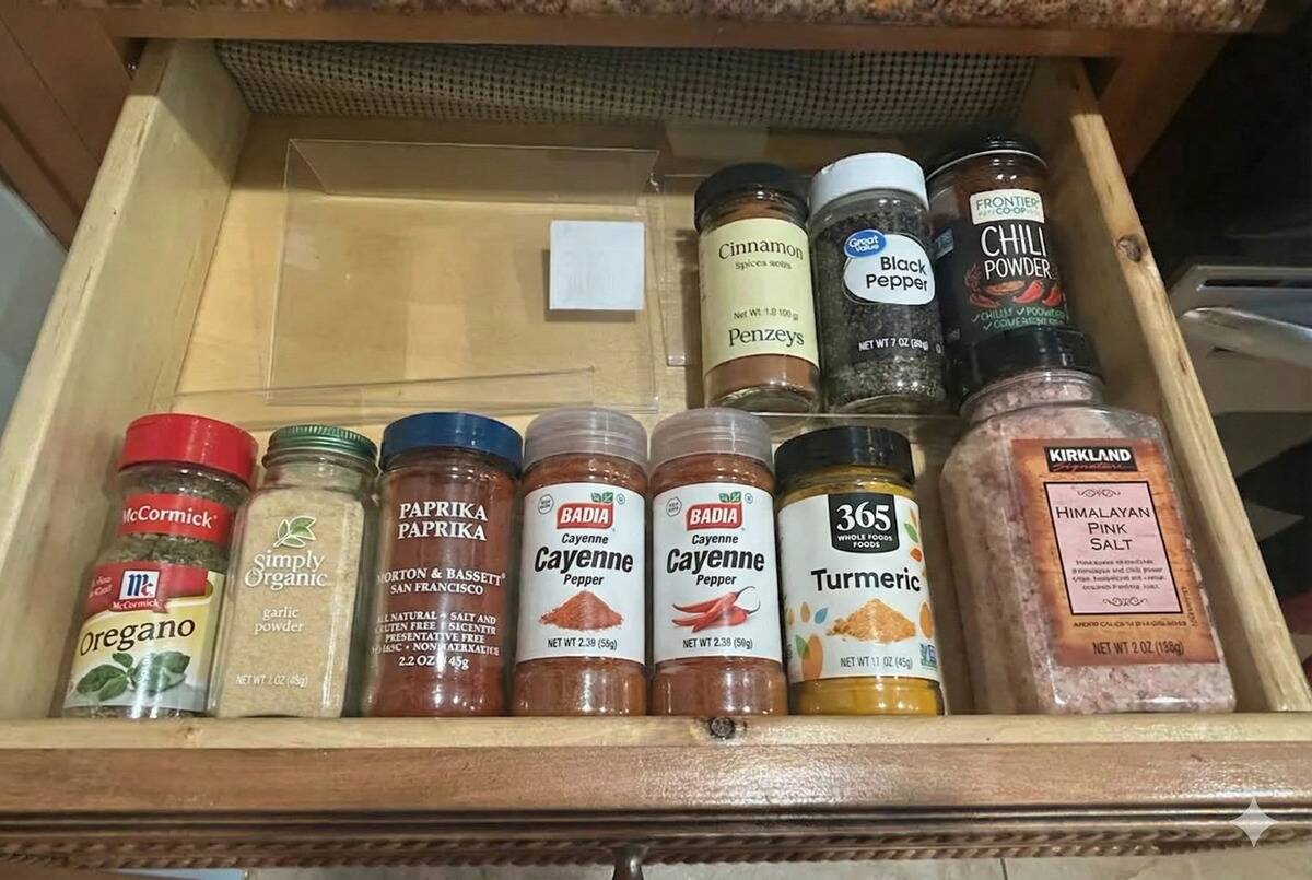 A clear plastic frame being used to organize spices in a drawer.
