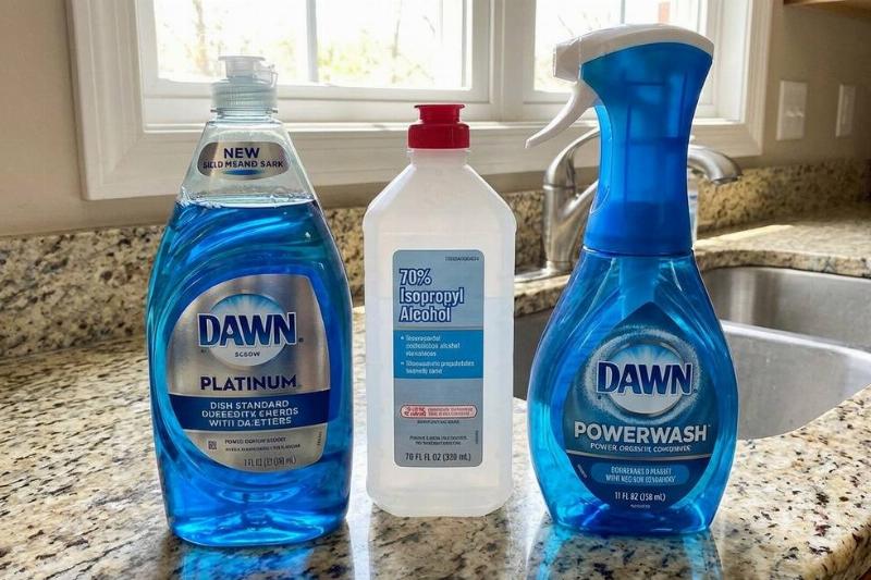 A bottle of Dawn Platinum, rubbing alcohol, and Dawn Powerwash on a kitchen counter. 