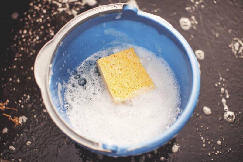 Soapy water with a sponge in it in a bucket. 