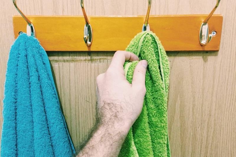 Hand reaching for towel drying on hook. 