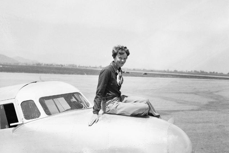 Amelia Earhart sitting on the nose of a plane
