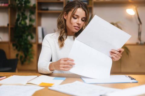 Woman looking through papers on her desk. 