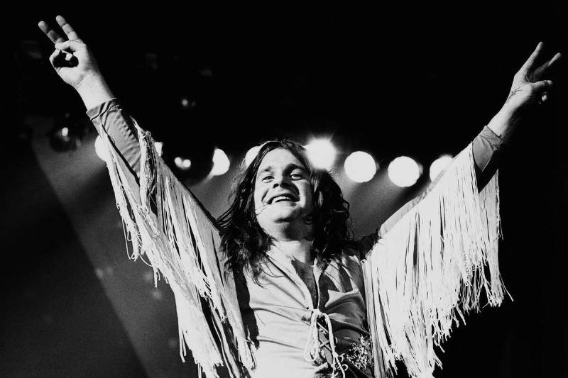 Ozzy Osbourne standing on stage, holding up two peace signs
