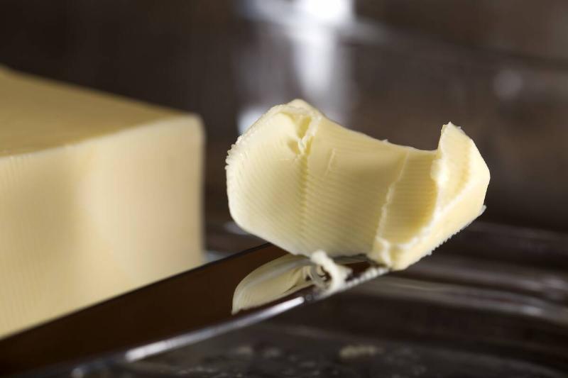 Knife with butter next to a stick of butter