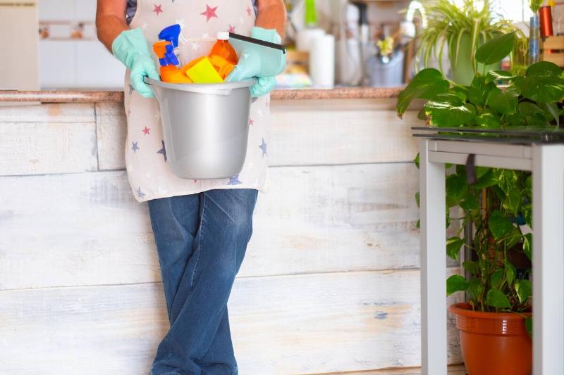 Man holding bucket of cleaning supplies