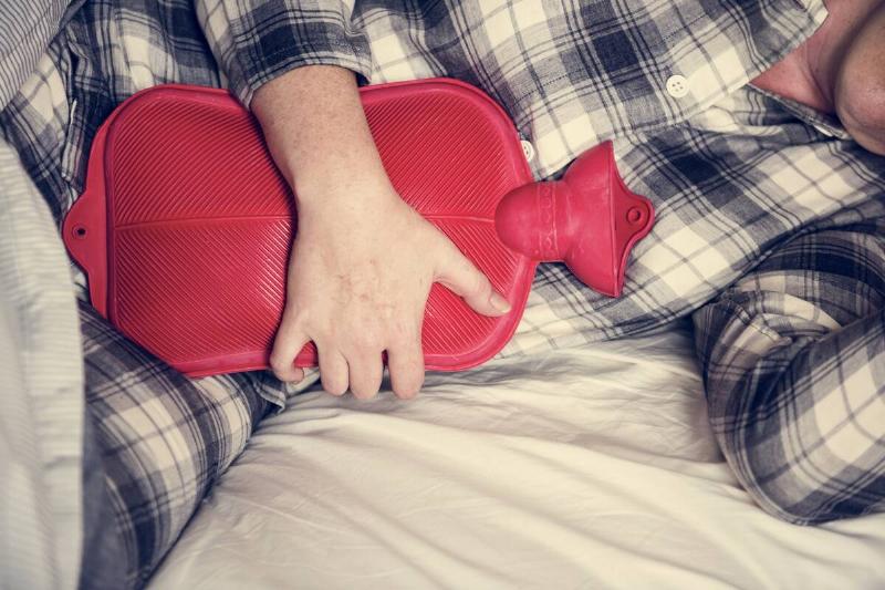 Person holding hot water bottle against themselves. 