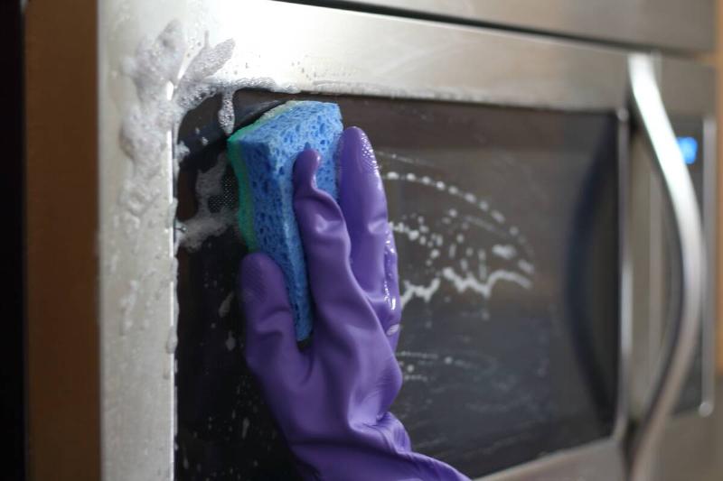 Person cleaning outside of microwave. 