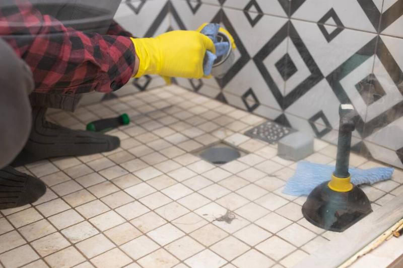 A man resealing the grout in his shower. 