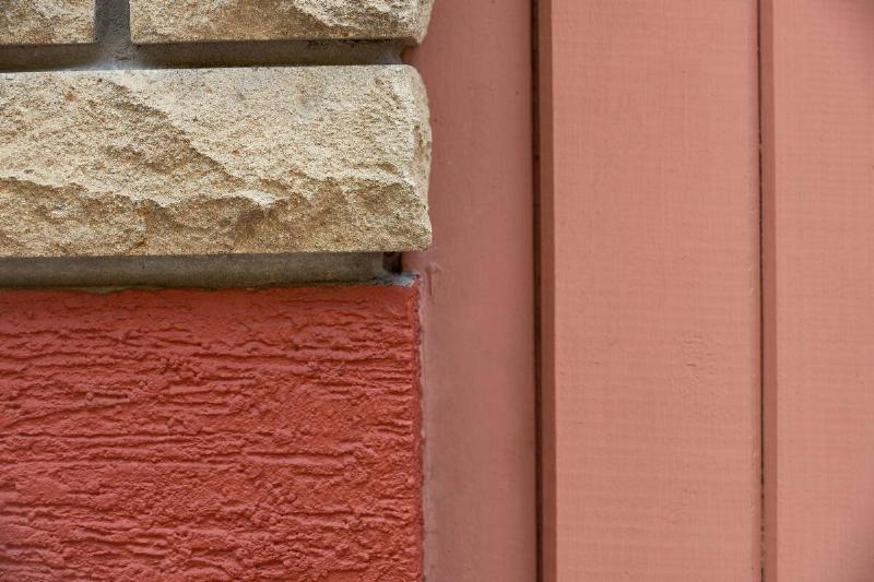 Cracks where brick meets siding, house exterior. 