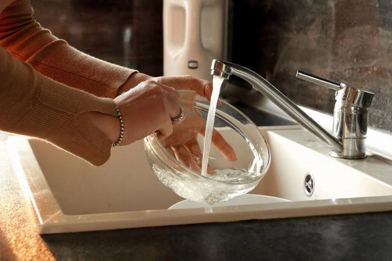 Hands rinsing off glass bowl. 