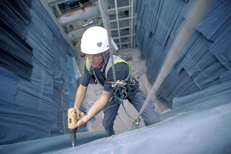 Construction worker abseiling the interior facade of the Kings College new hospital, south London