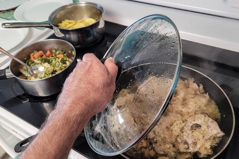 Person removing glass lid from pot. 