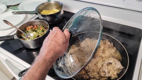 Person removing glass lid from pot. 