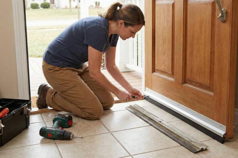 Woman replacing the door sweep on a door. 