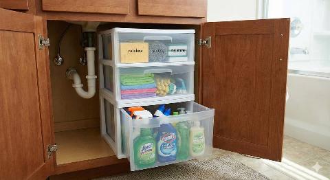 Stackable plastic drawers holding cleaning supplies under a bathroom sink.