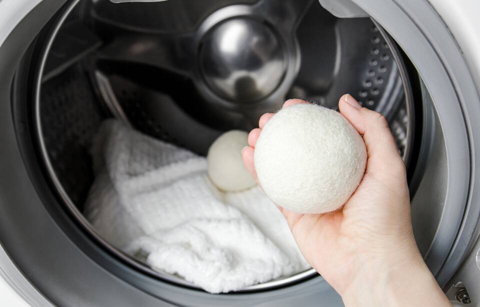A hand putting dryer balls in the dryer.