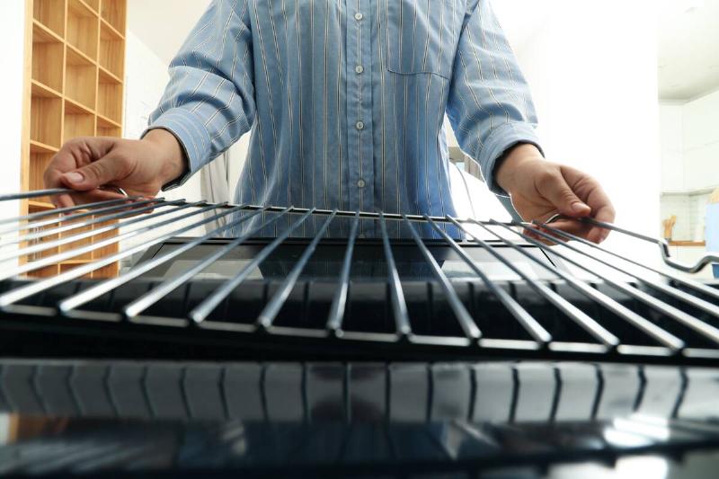 Hands removing racks from oven. 