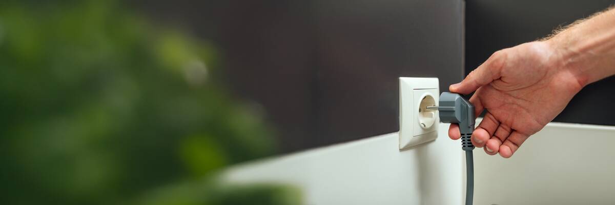 Hand unplugging cord from socket. 