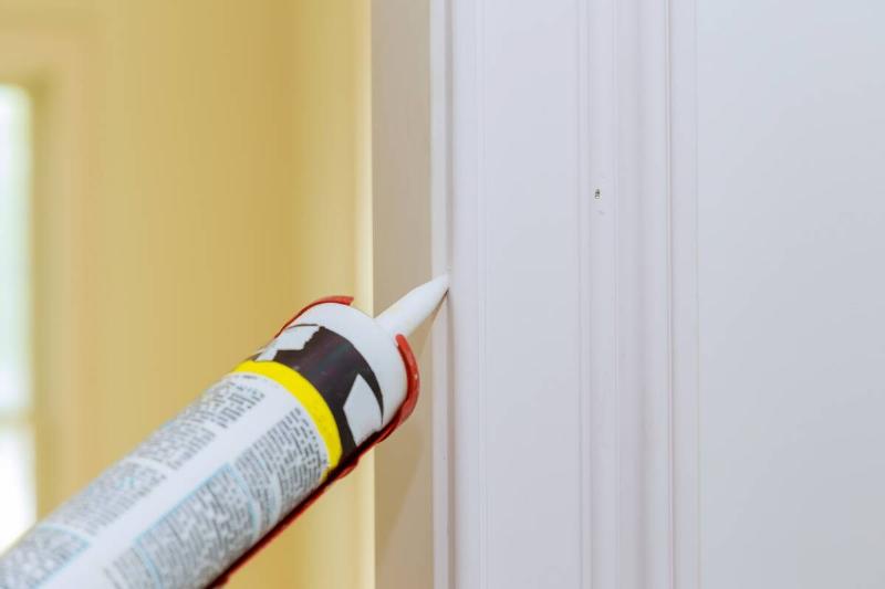 Applying caulk around door molding. 