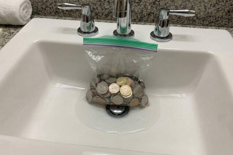 A bag of coins blocking the drain of a hotel sink. 