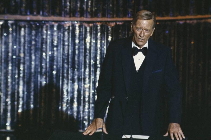 John Wayne speaking at a podium