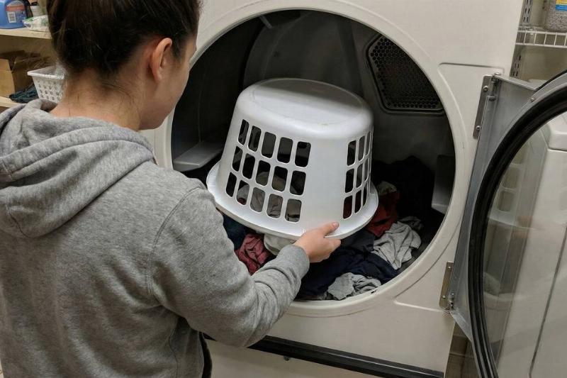 A person putting a laundry basket into a dryer. 