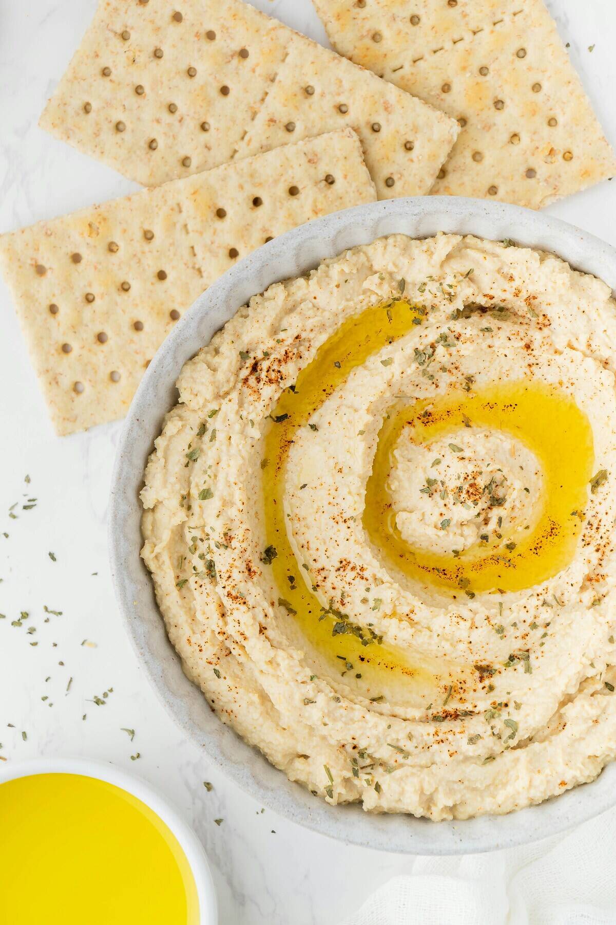 Crackers placed next to bowls of dip and oil 