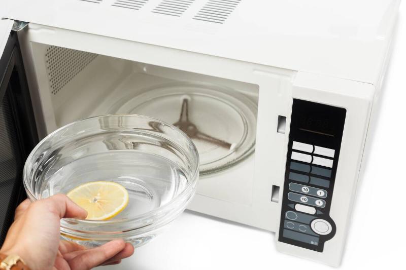 A bowl of water being placed in a microwave. 
