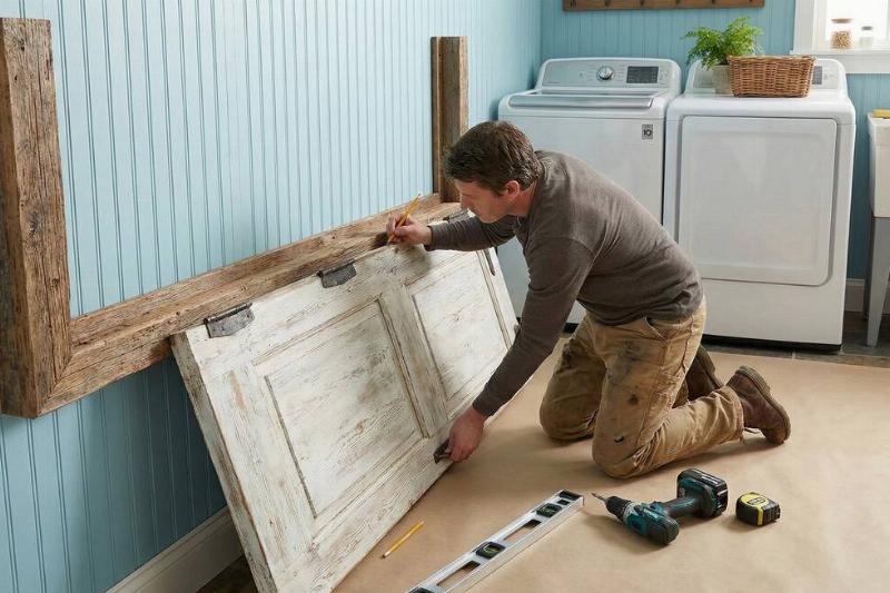 A man mounting a door on the wall. 