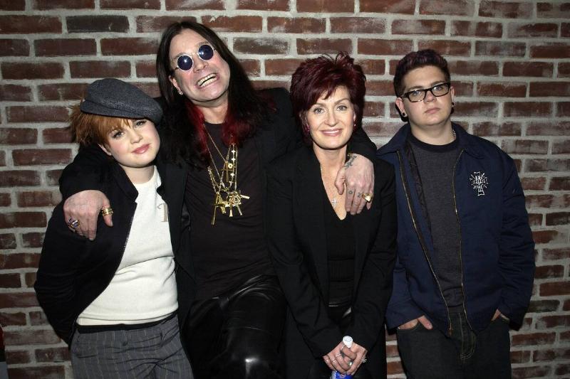 Kelly, Ozzy, Sharon and Jack Osbourne standing in front of a brick wall
