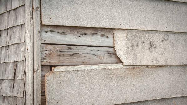 Rotting wood and peeling siding on house. 