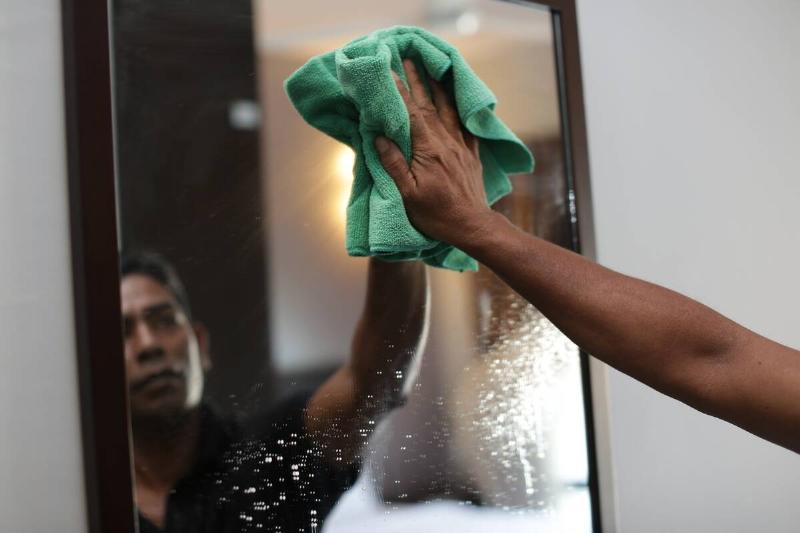 Person washing mirror. 