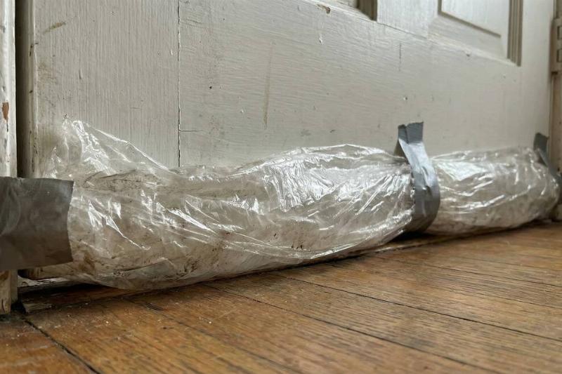 Plastic wrap used to seal the gap under a door. 