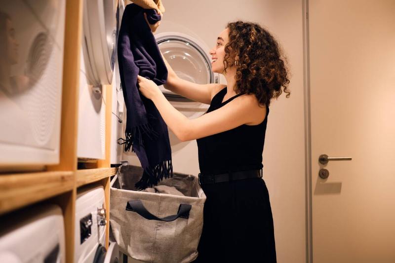Woman putting clothes into dryer. 