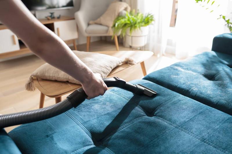 Person vacuuming couch. 