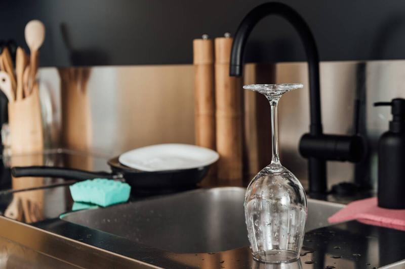 A wine glass air drying on a counter near a sink. 