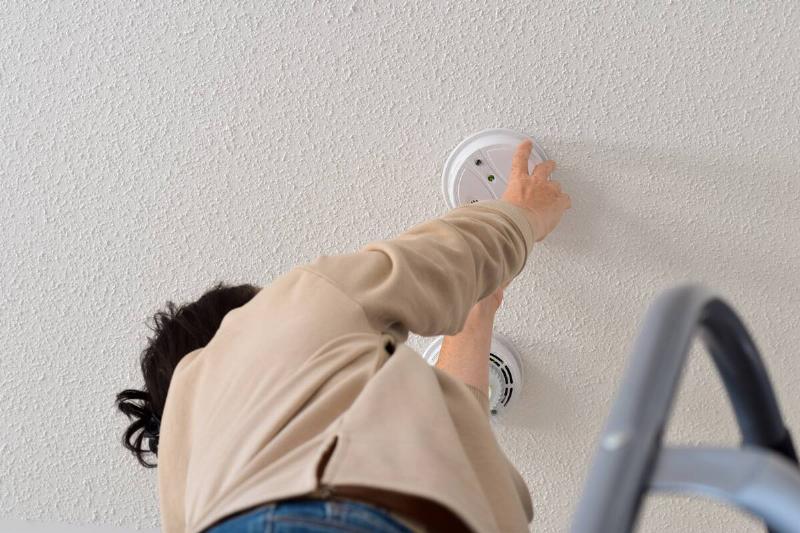 Woman replacing batteries in her smoke detector. 