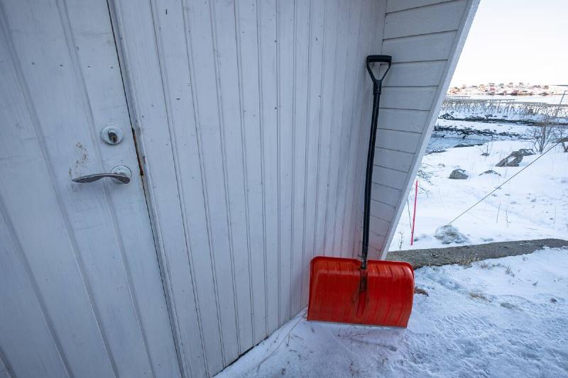 Snow shovel put on front of a wooden house in winter.