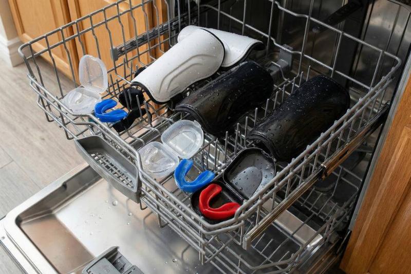 Sports equipment on the top rack of a dishwasher. 